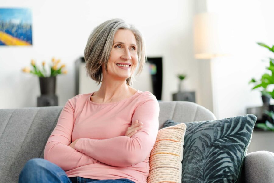 Smiling woman with silver hair relaxing on a sofa